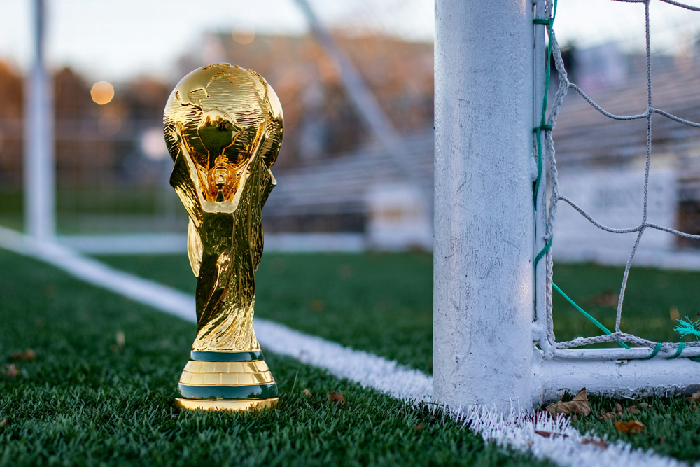 Footballers Community | A golden football trophy sitting on the top of a football field photo
